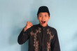 © Lailar Studio - Excited young Asian Muslim man raising fists and celebrating victory on Ramadan and Eid Mubarak