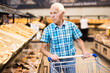 © caftor - Elderly man buying bread and pastries in grocery section of the supermarket