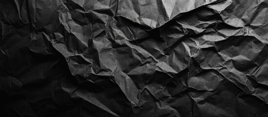 Poster - Crumpled black paper background with deep folds and texture creating a grunge effect capturing shadows and highlights for artistic use
