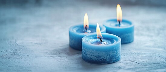 Aufkleber - Burning blue candles in varying heights on a textured light blue background with soft shadows creating a serene atmosphere and space for text.