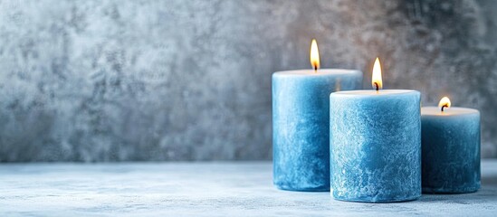 Leinwandbilder - Blue burning candles in varying heights arranged on a textured gray background with warm candlelight creating a serene atmosphere for text.