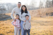 © Vasil - A family of four posing for a picture in a field. Scene is happy and warm