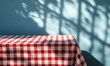 © El Media - Empty Table with Red Checkered Tablecloth and Shadow Overlay on Wall