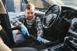 © Serhii - Feeling happy to be doing an excellent job at my job at the car wash. Portrait of a man while sitting inside a customer vehicle