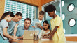 © InfiniteFlow - Caucasian teacher giving comment or advise student while smart bot pointing at laptop screen at classroom. Diverse student taking a note while teacher teach lesson while using computer. Edification.