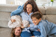 © Nanci - Mother and children are spending quality time together at home, tickling and laughing on the sofa, enjoying a playful and affectionate moment of family bonding