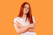 © Iryna - Young woman confidently posing against a bright orange background showcasing a fun and playful attitude with expressive hand gestures
