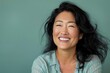 © Markus Schröder - Portrait of a smiling asian woman in her 40s laughing while standing against soft green background