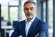 © Wannaeka - Portrait of a confident middle aged man in blue suit standing in bright modern office with serious expression