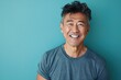 © Markus Schröder - Portrait of a blissful asian man in his 40s smiling at the camera isolated on soft teal background