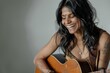 © Markus Schröder - Portrait of a grinning indian woman in her 30s playing the guitar in soft gray background