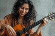 © Markus Schröder - Portrait of a grinning indian woman in her 30s playing the guitar while standing against soft gray background