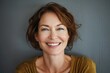 © Markus Schröder - Portrait of a happy caucasian woman in her 40s smiling at the camera while standing against soft gray background