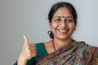 © Markus Schröder - Portrait of a jovial indian woman in her 40s showing a thumb up isolated in soft gray background
