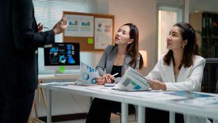 Poster - Professional Asian businesswomen collaborating, reviewing financial charts, strategizing marketing plans in contemporary workspace