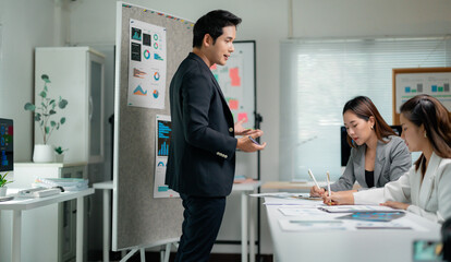 Poster - Businessman presenting marketing data to colleagues taking notes during a meeting in the office