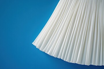 Aufkleber - White pleated fabric draped against a vibrant blue background showcasing texture and movement