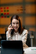 © Parichat - Focused businesswoman working late at night in office using tablet and talking on mobile phone