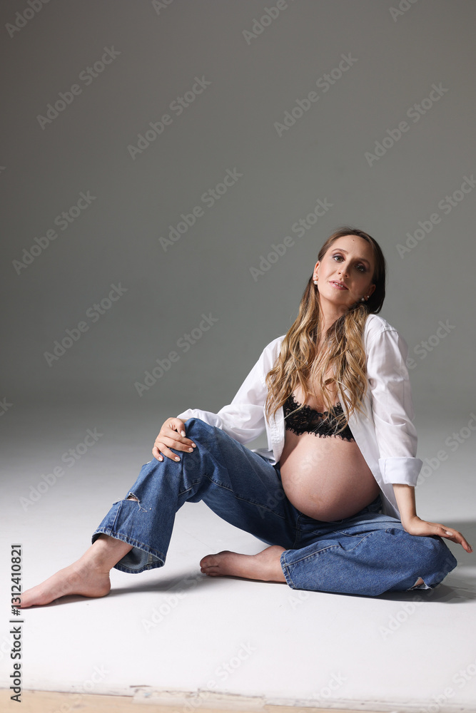 Foto de Stock Portrait of attractive pregnant woman in shirt, jeans, with naked belly, studio