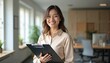 © miss irine - Happy young woman, psychologist holds clipboard in office, looks, smiles at camera. Portrait of confident pro businesswoman in suit. Successful female coach, trainer, consultant at workplace during