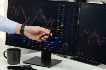 cropped hand of businessman pointing to dynamic stock exchange data at red point by holding pen on c