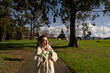 © asier - Chic woman in beige coat and emerald top walking through lush greenery, basking in sunlight and breathing crisp outdoor air
