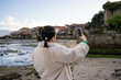 © asier - Young woman tourist capturing stunning photos in combarro, a picturesque coastal town in galicia, spain, immersing herself in the vibrant culture and scenic beauty of her travels
