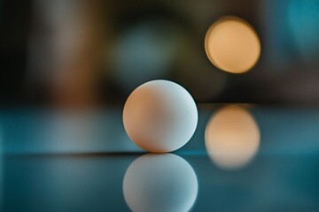 Wall Mural - white sphere reflecting on a glossy surface with bokeh lights.