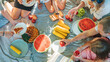 © Soloviova Liudmyla - Top view of big family sitting on the picnic blanket in city park. They are eating boiled corn, apples, peaches, pastries and watermelon. Family values and outdoor activities concept
