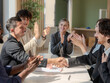 © HEPJAM studio - Business team shows unity by shaking hands in sunny conference room. Group of people holding hands and representing the concept of friendship and teamwork.