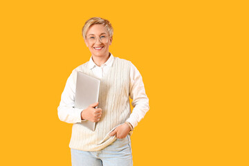 Mature female programmer with laptop on yellow background