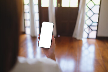 Wall Mural - mockup image of a woman holding mobile phone with blank desktop screen at home