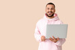© Pixel-Shot - Smiling young man with laptop on beige background