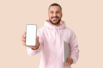 Wall Mural - young man with mobile phone and laptop on beige background