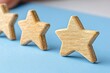 © MILKY_PS - In the image, a trio of golden wooden stars gleam brightly, set against a light blue background They symbolize excellence, achievement, and recognition within a corporate setting Each star signifies