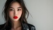 © oris - Close-up portrait of a young Asian woman with red lips and black leather jacket.
