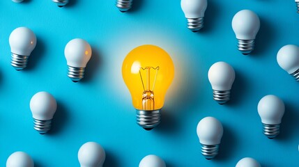 Leinwandbilder - A glowing yellow light bulb surrounded by white bulbs on a blue backdrop, illustrating creativity, innovation, and the illumination of new ideas