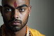 © whitestorm - A focused portrait of a young Indian man with traditional tilak, revealing cultural heritage, a blend of traditional and modern styles, with a light gray background.