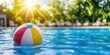 © Gibster - Happy summer beach fun and lifestyle. Colorful beach ball floating in a sunny pool surrounded by greenery.