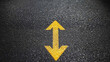 © NongKirana - Yellow double arrow on textured asphalt road surface, indicating two way traffic