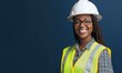 © shirophoto - A smile female construction worker in an yellow safety vest and white hard hat, standing against a solid dark blue background, professional and strong posture