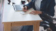 © tippapatt - Young asian business woman working on laptop computer and writing on notepad on table at coffee shop. Smiling freelancer online working, planning new project, freelance at work