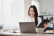 © PRIME STOCK LAB - Confident Asian Businesswoman Multitasking With Laptop and Tablet in Bright Office.