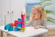 © KseniaJoyg - A little child girl plays a sorter, a construction kit, or an educational game at a table in a room