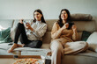 © Dusan - Young caucasian woman and her sister play video games on joystick and eat pizza