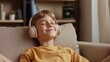 © Mrammon - A young boy is wearing headphones and smiling while sitting on a couch