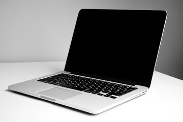 Leinwandbilder - A sleek silver laptop with a black screen sits on a white table against a neutral background.