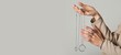 © Pixel-Shot - Hands of woman with silver jewelry on grey background with space for text