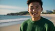 © Alteisen Riese - Good-looking young asian guy in green themed sweater on a beach smiling