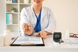 © Pixel-Shot - Female doctor with hearing aid at desk in office, closeup